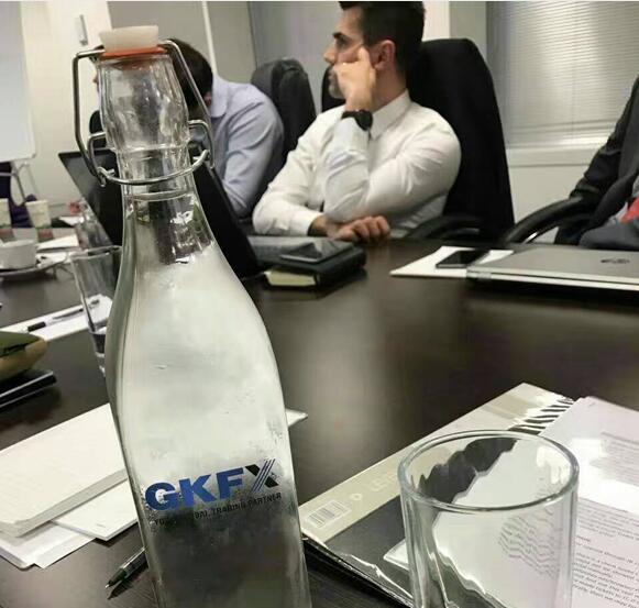 会议室桌上摆放的一只印制GKFX捷凯金融的Logo的玻璃水瓶，优雅的英伦范。